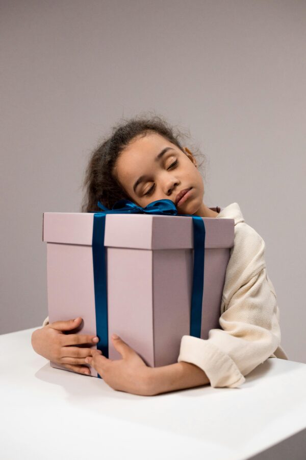 Sweet moment of a child embracing a large gift box, eyes closed in bliss.